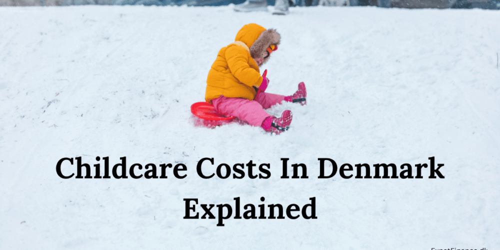 A young toddler wearing a bright yellow winter jacket and pink snowpants sledding down a snowy hill in Denmark, featuring the text overlay "Childcare Costs In Denmark Explained."
