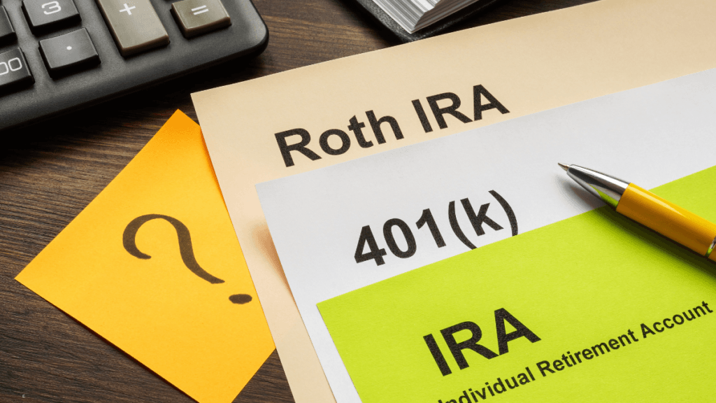 Roth IRA, 401(k), and IRA retirement account documents with a calculator and pen on a desk
